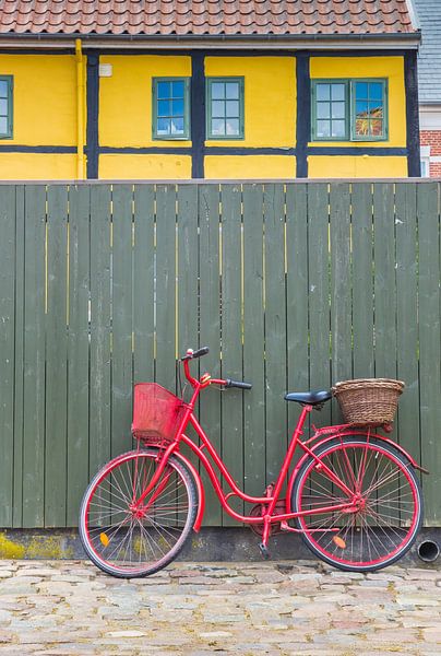 Rode fiets staat voor een groene schutting in Ribe Denemarken van Marc Venema