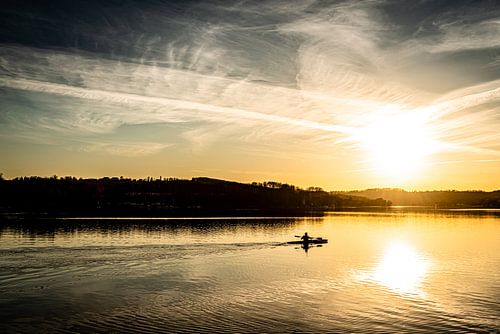Baldeneysee in Essen met roeiers in de winter tegen het licht bij zonsondergang