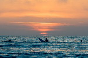 Les surfeurs admirent le coucher de soleil dans l'eau à Terschelling sur Alex Hamstra