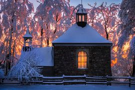 Snow-Covered Chapel at Sunset with Warm Light in Winter Forest in High Fens of Belgium by Arda Acar