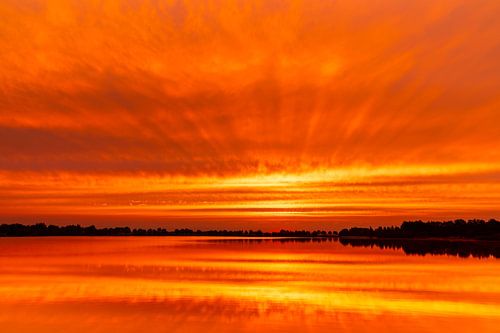 Een lanschap waarop we ochtendrood zien we weerspiegelen in het water; red dawn