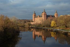Schloss Johannisburg am Ufer des Mains mit Spiegelung im dunkelblauen Wasser, berühmtes historisches