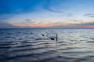 Sonnenuntergang über einem See, mit sichtbarer Wasserbewegung. von Jan van Broekhoven