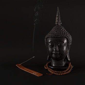 Buddha mit Weihrauch vor schwarzem Hintergrund