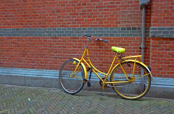 Gele fiets tegen een rode muur