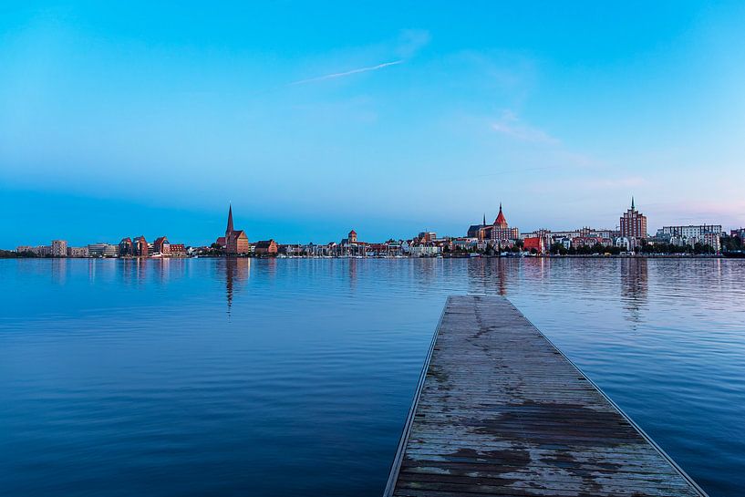 Uitzicht over de Warnow naar de Hanzestad Rostock bij avond van Rico Ködder