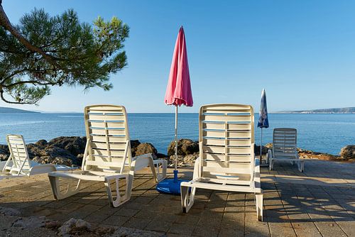 Parasol en ligstoelen aan de Adriatische kust bij de stad Krk