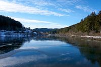 Rivière gelée avec de la neige et de la glace ensoleillée sous un ciel bleu au Nagoldtalsperre
