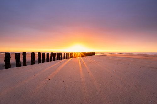 Zonneschijn door de golfbrekers op het Zeeuwse strand van Jolanda de Leeuw
