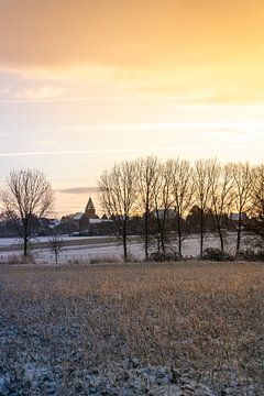 Gouden ochtend in een winters landschap met kerk en sneeuw van Mickéle Godderis