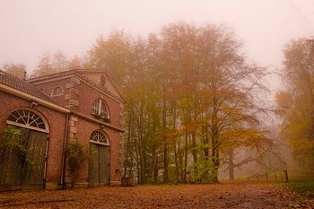 Herbstwald im Nebel mit altem Kutschenhaus