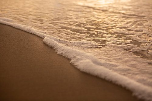 ebener Sandstrand mit weißem Schaum vom Meer
