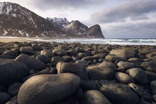 Rotsen en golven op het strand van Unstad onder de majestueuze bergen van de Lofoten'
