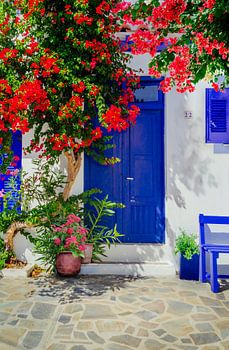 Traditionelles weißes Haus mit blauen Türen und Blumen, Griechenland