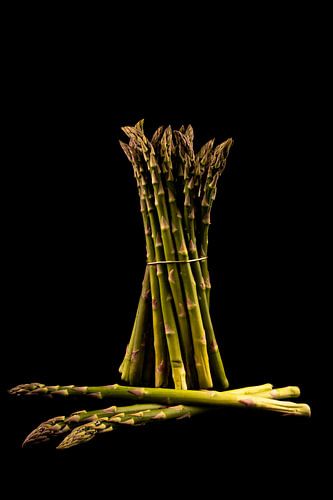 Standing and lying fresh green asparagus with a black background