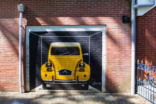 Yellow Citroen 2CV painted on a red brick wall
