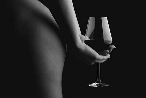 Ein Bild einer nackten Frau, die ein Glas Wein hinter ihrem Rücken hält.