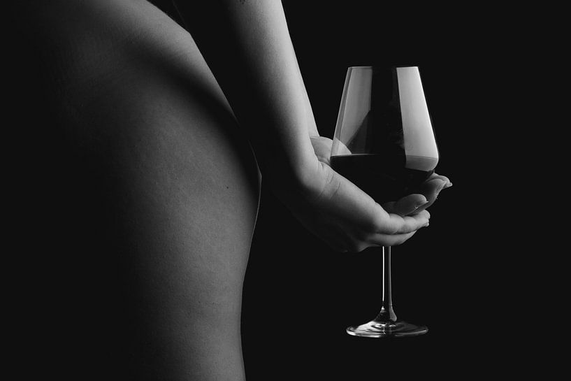 Een foto van een naakte vrouw die een glas wijn vasthoudt achter haar rug.  van Retinas images