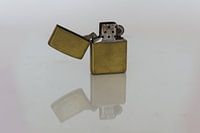 Een vintage Zippo op een spiegelende ondergrond.