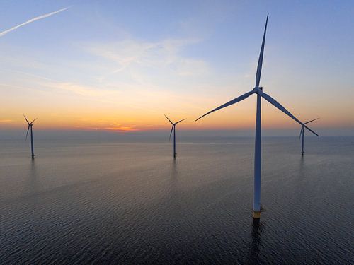 Windmolens in een offshore windpark tijdens zonsondergang