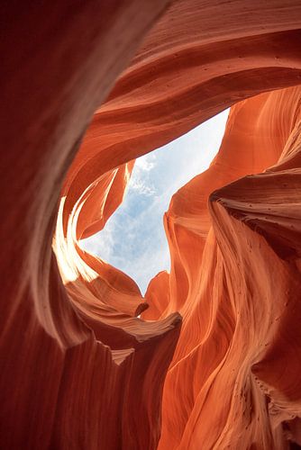 Oranje en bruine rotswand met doorkijk naar lucht