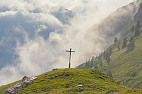 Kruis in een mistig Alpen landschap