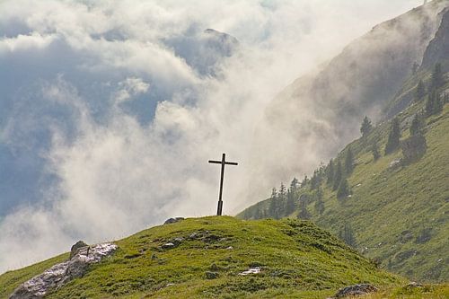 Kruis in een mistig Alpen landschap