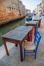 Tische und Stühle an einem Kanal mit Booten im alten Zentrum von Venedig, Italien von Joost Adriaanse Miniaturansicht