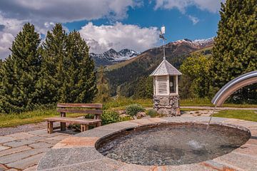 Holzbank bei einem Brunnen inmitten der Berge von Dafne Vos