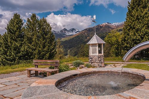 Holzbank bei einem Brunnen inmitten der Berge