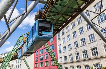 Zweeftrein (monorail) glijdt langs historische gebouwen in Wuppertal van Marc Venema