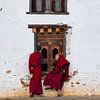 Des moines regardent par la fenêtre d'un monastère au Bhoutan. sur Teun Janssen