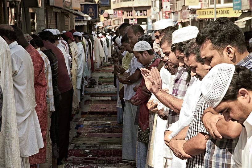 Moslim samen buiten bidden op een straat in Dubai van Tjeerd Kruse