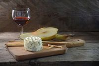 cremig-blauer Stiltonkäse, Portwein, Birne und einige Knabberstangen auf einem Schneidebrett vor ein