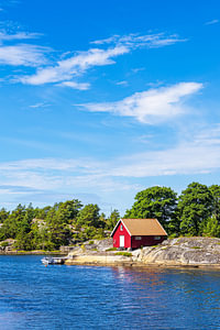 Rote Holzhütte und Bäume an der Küste der Insel Rossö nahe S