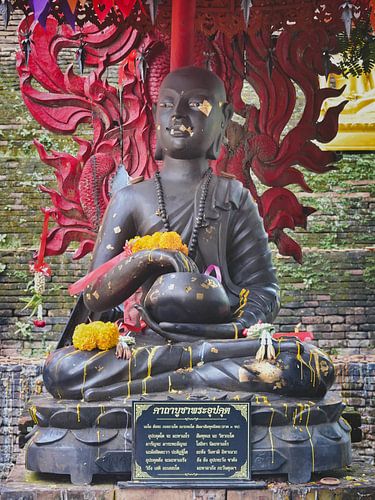 Buddhistische Mönchsstatue mit Blumenopfer