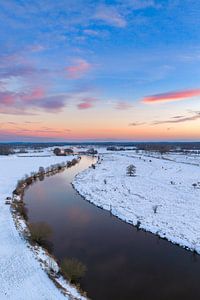 Der Fluss Vecht fließt durch eine verschneite Winterlandschaft bei Sonnenschein.
