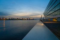 Uitzicht langs de zijkant van het Dockland naar de verlichte kranen van de haven van Hamburg tijdens