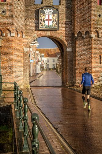 View of the Koppelpoort in Amersfoort with a jogger in the foreground. by Bart Ros