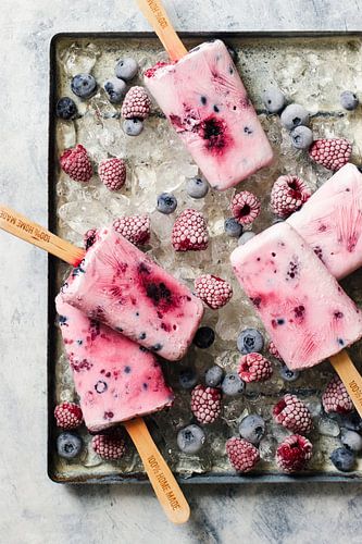 12544947 Zelfgemaakte ijsjes van yoghurt, honing en bessen, frambozen en bosbessen op ijs