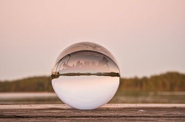 Glaskugel auf einem Steg der in einen See reicht von Martin Köbsch