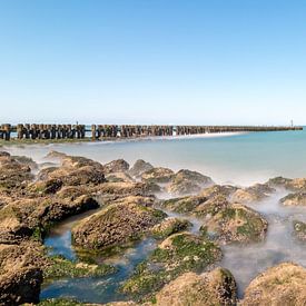 Stromend water van de zee rondom stenen op het strand van Josephine Huibregtse