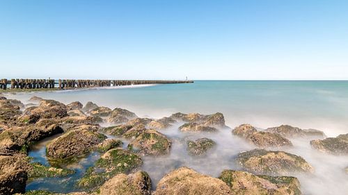 Flowing water of the sea around stones on the beach