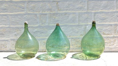 Bouteilles vertes contre un mur blanc