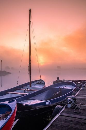 Mistige zonsopkomt aan het water met kleine bootjes