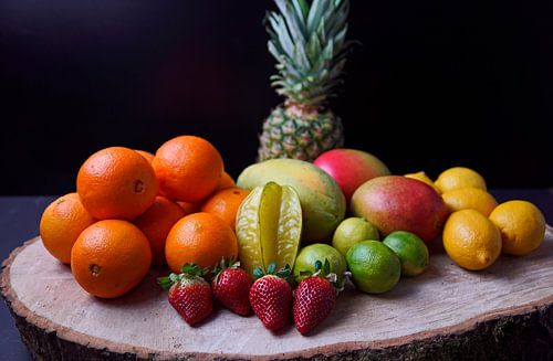 Sinaasappels, mango's, papaja's, aardbeien, ananas, limoenen en citroenen op een houten schijf