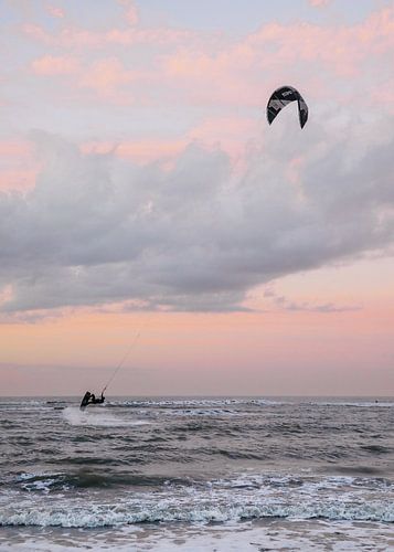 Kitesurfer met een pastel kleurige zonsondergang bij de zee in Ouddorp