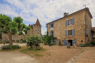 Square with castle and shop in Saint-Jean-de-Côle, France by Joost Adriaanse