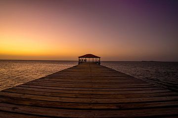 Geel met paarse zonsondergang op de pier aan het strand van Reis Genie