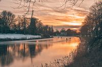 Zonsondergang met molen, schaatsers en ijs